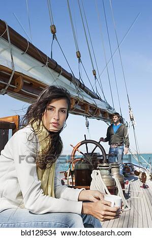 Picture - Caucasian woman drinking coffee on sailboat. Fotosearch