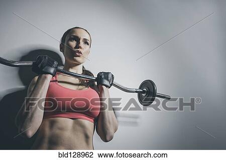 Stock Image - Caucasian woman lifting barbell. Fotosearch