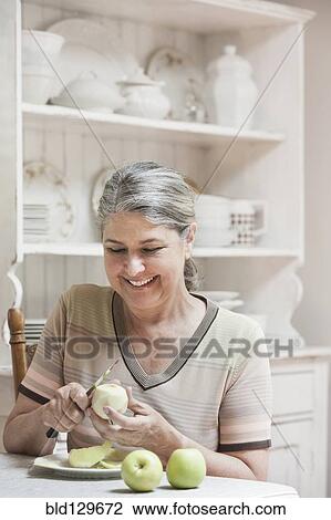 Caucasian woman peeling fruit in kitchen View Large Photo Image Stock Image - Caucasian woman peeling fruit in kitchen. Fotosearch