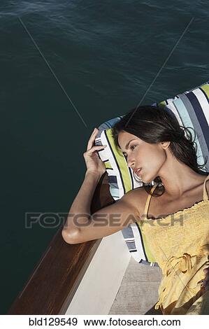 Stock Photo - Caucasian woman relaxing on sailboat. Fotosearch