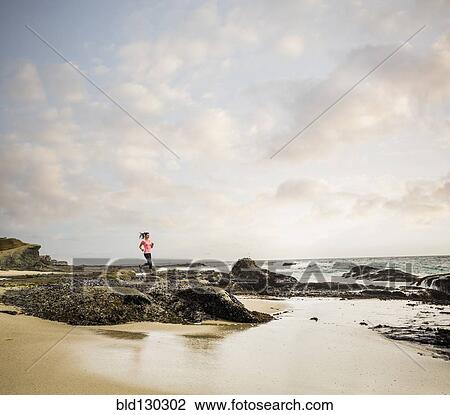 Stock Image - Caucasian woman running on beach. Fotosearch
