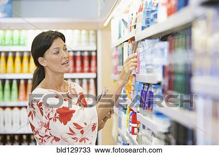 Stock Image - Caucasian woman shopping in drugstore. Fotosearch
