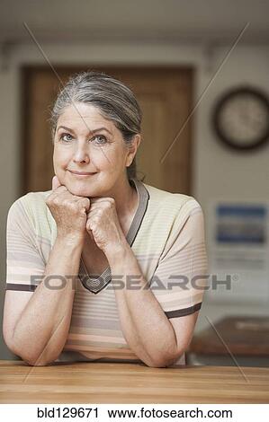 Stock Image - Caucasian woman sitting at table. Fotosearch