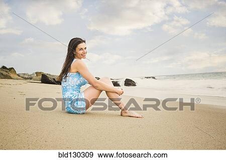 Stock Photo - Caucasian woman sitting on beach. Fotosearch