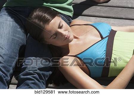 Stock Image - Caucasian woman sleeping on wooden dock. Fotosearch