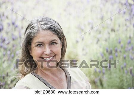 Stock Image - Caucasian woman smiling in lavender field. Fotosearch
