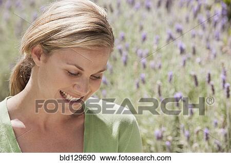 Stock Image - Caucasian woman smiling in lavender field. Fotosearch