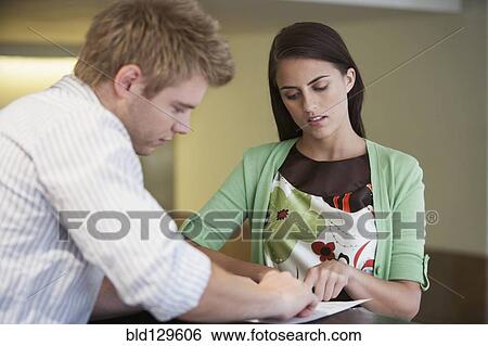 Stock Photograph - Caucasian woman talking to receptionist in hotel lobby. Fotosearch