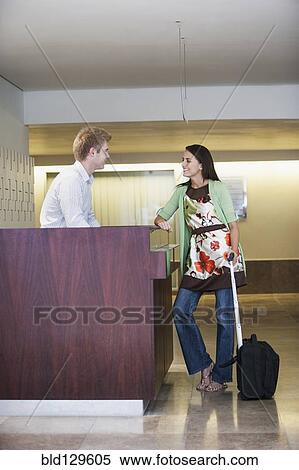 Stock Photography - Caucasian woman talking to receptionist in hotel lobby. Fotosearch