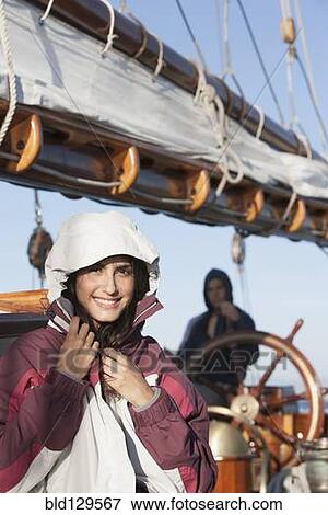 Stock Photo - Caucasian woman wearing jacket on sailboat. Fotosearch
