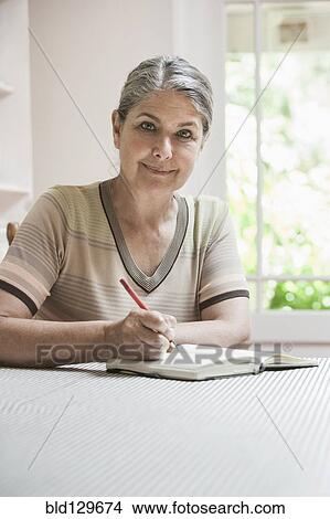 Picture - Caucasian woman writing in journal. Fotosearch