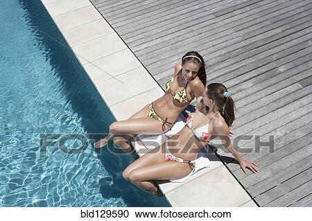 Caucasian women relaxing by swimming pool View Large Photo Image Stock Image - Caucasian women relaxing by swimming pool. Fotosearch