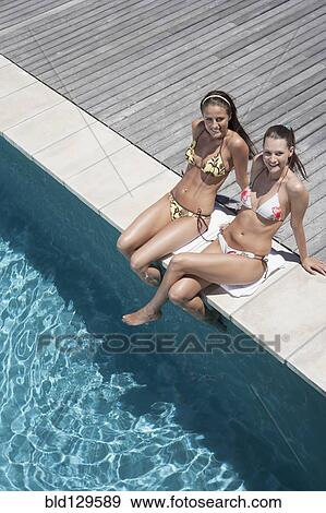 Caucasian women relaxing by swimming pool View Large Photo Image Stock Photo - Caucasian women relaxing by swimming pool. Fotosearch
