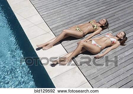 Caucasian women sunbathing by swimming pool View Large Photo Image Stock Image - Caucasian women sunbathing by swimming pool. Fotosearch
