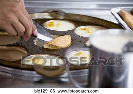 Stock Photograph - Chef flipping banana pancakes in restaurant. Fotosearch