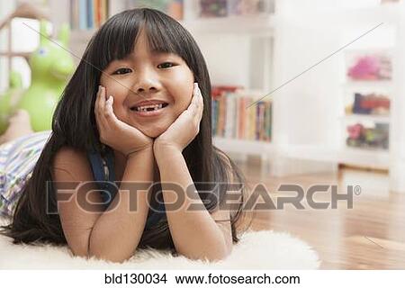 Picture - Chinese girl laying with chin in hands. Fotosearch
