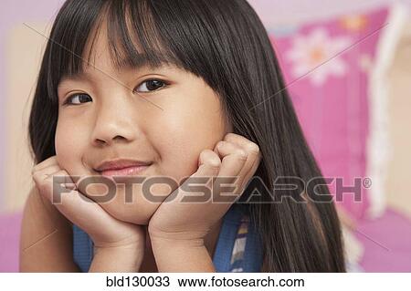 Stock Image - Chinese girl laying with chin in hands. Fotosearch