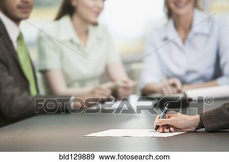 Stock Photo - Close up of businesswoman making notes in meeting. Fotosearch