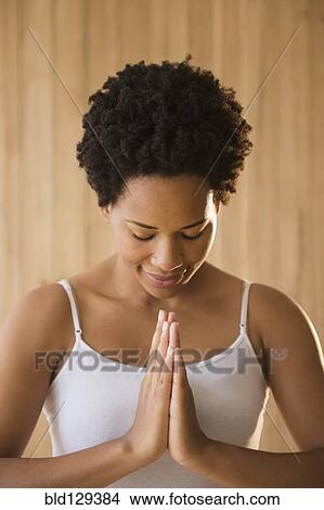 Picture - Close up of serene Black woman with hands in prayer position. Fotosearch