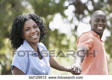 Stock Image - Couple holding hands in park. Fotosearch
