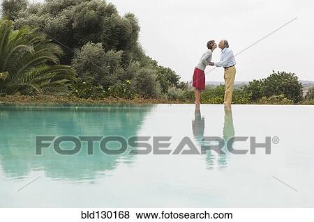 Stock Photo - Couple kissing by infinity pool. Fotosearch