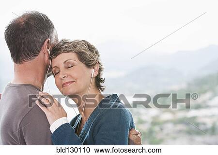 Stock Image - Couple listening to earphones together. Fotosearch