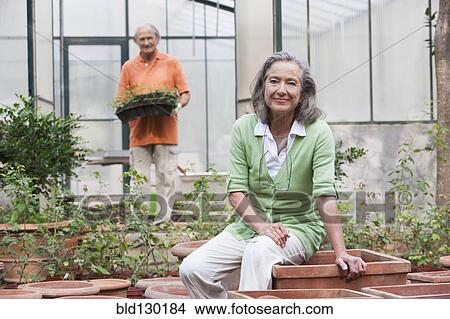 Picture - Couple potting plants in greenhouse. Fotosearch