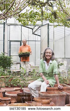 Stock Photography - Couple potting plants in greenhouse. Fotosearch