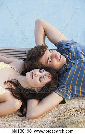 Stock Photo - Couple relaxing by swimming pool. Fotosearch