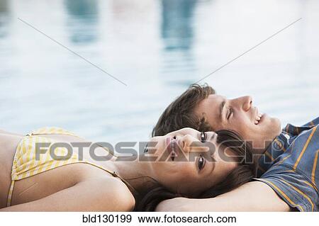 Stock Photo - Couple relaxing by swimming pool. Fotosearch