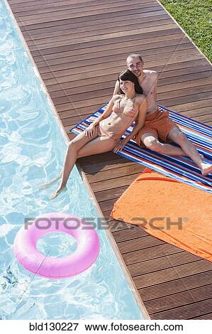 Couple relaxing together by swimming pool View Large Photo Image Stock Photo - Couple relaxing together by swimming pool. Fotosearch