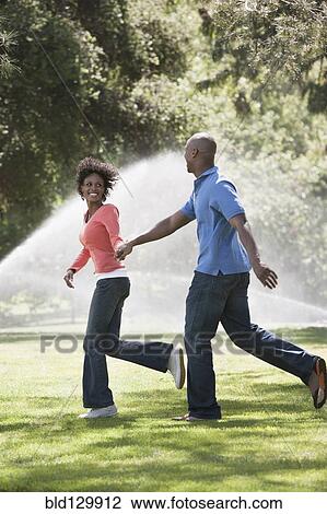 Stock Image - Couple running in park. Fotosearch