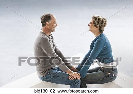 Stock Image - Couple sitting together on benches. Fotosearch
