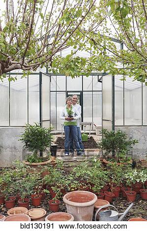 Stock Image - Couple smiling in greenhouse. Fotosearch