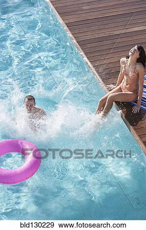 Stock Photo - Couple splashing in swimming pool. Fotosearch