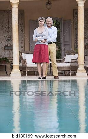 Couple standing by swimming pool View Large Photo Image Stock Photo - Couple standing by swimming pool. Fotosearch