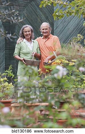 Stock Photograph - Couple tending plants in greenhouse. Fotosearch