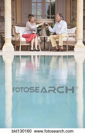 Couple toasting each other by swimming pool View Large Photo Image Stock Image - Couple toasting each other by swimming pool. Fotosearch