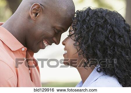 Stock Photograph - Couple touching foreheads outdoors. Fotosearch