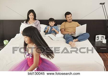 Stock Photography - Family relaxing together in bedroom. Fotosearch