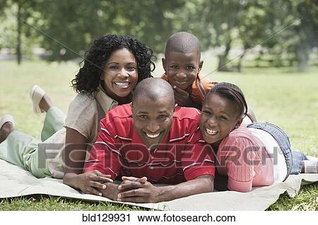 Stock Image - Family relaxing together in park. Fotosearch