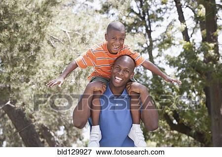 Stock Photo - Father carrying son on shoulders in park. Fotosearch