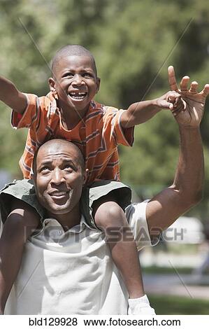 Father carrying son on shoulders in park View Large Photo Image Stock Photo - Father carrying son on shoulders in park. Fotosearch
