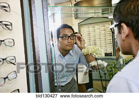 Filipino man trying on glasses at optometrist View Large Photo Image Stock Photo - Filipino man trying on glasses at optometrist. Fotosearch