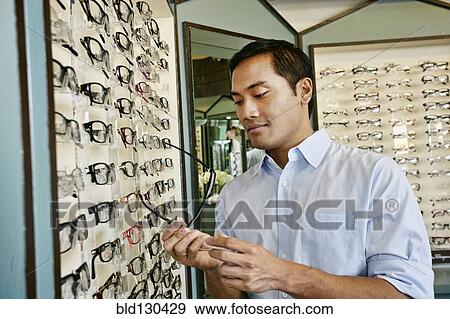 Filipino man trying on glasses at optometrist View Large Photo Image Stock Photo - Filipino man trying on glasses at optometrist. Fotosearch