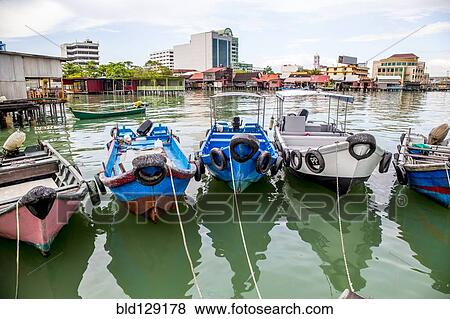 Stock Photo - Fishing boats docked in urban harbor. Fotosearch