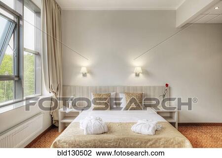 Stock Image - Folded robes on bed in hotel room. Fotosearch
