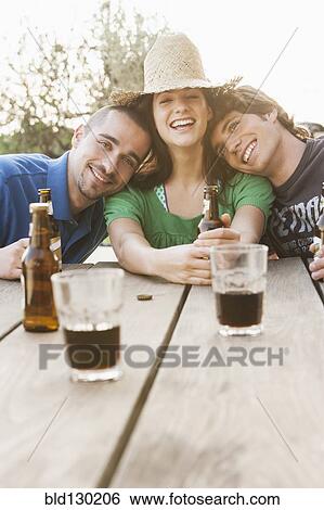 Stock Photograph - Friends drinking beer together outdoors. Fotosearch