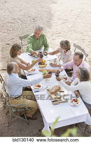 Stock Image - Friends eating together outdoors. Fotosearch