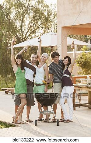 Stock Image - Friends having barbecue outdoors. Fotosearch